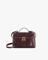 Sac VAYA Aubergine de face, anse courte, breloques Key Bell dorées et étiquette cuir sur le zip