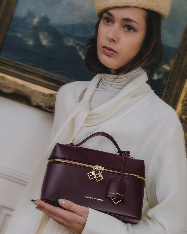 Sac VAYA Aubergine porté à la main, vue de face avec breloque Key Bell et étiquette cuir