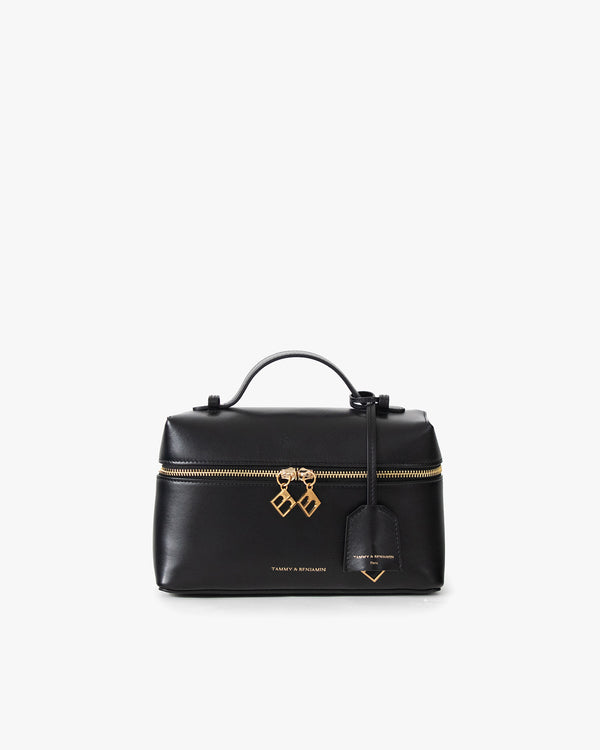 Sac VAYA noir de face, anse courte relevée, zip fermé avec breloques dorées et étiquette bagage