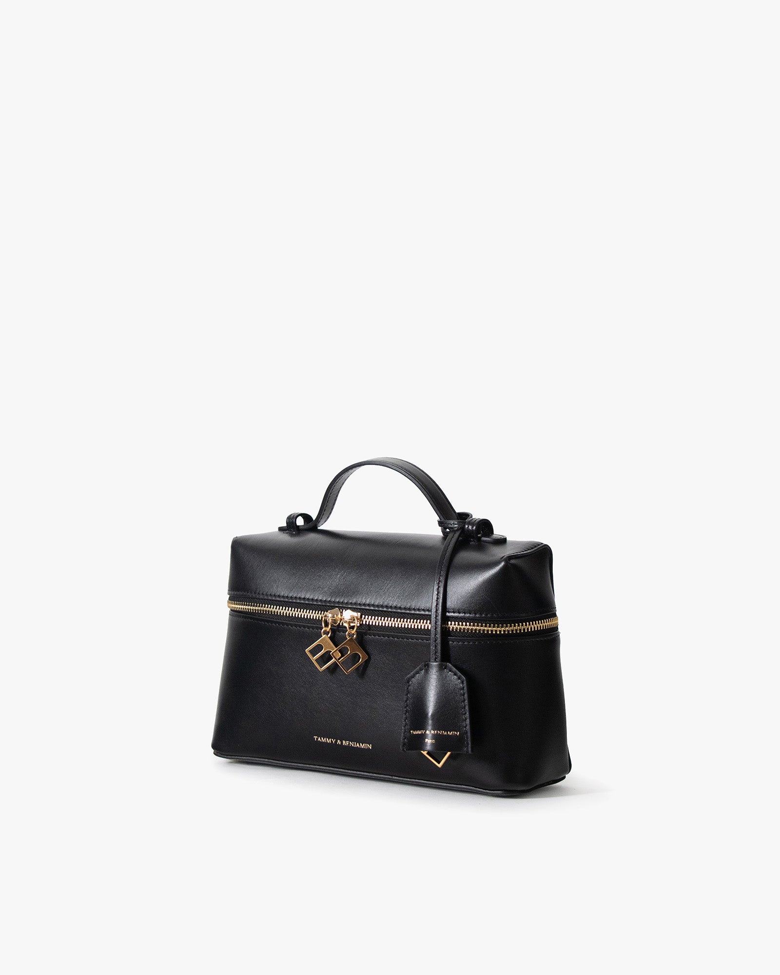 Sac VAYA noir, vue de trois quarts, poignée courte, zip doré et breloques BB, porté-main