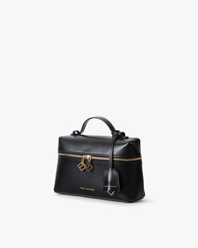 Sac VAYA noir, vue de trois quarts, poignée courte, zip doré et breloques BB, porté-main