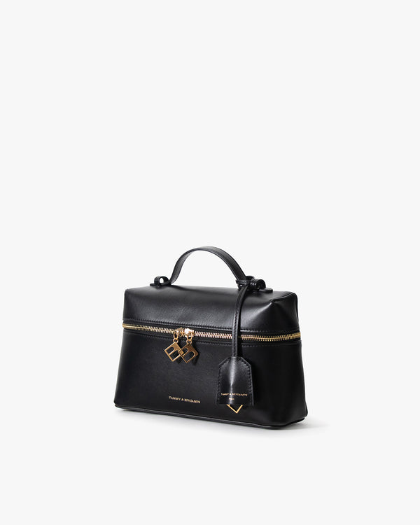 Sac VAYA noir, vue de trois quarts, poignée courte, zip doré et breloques BB, porté-main