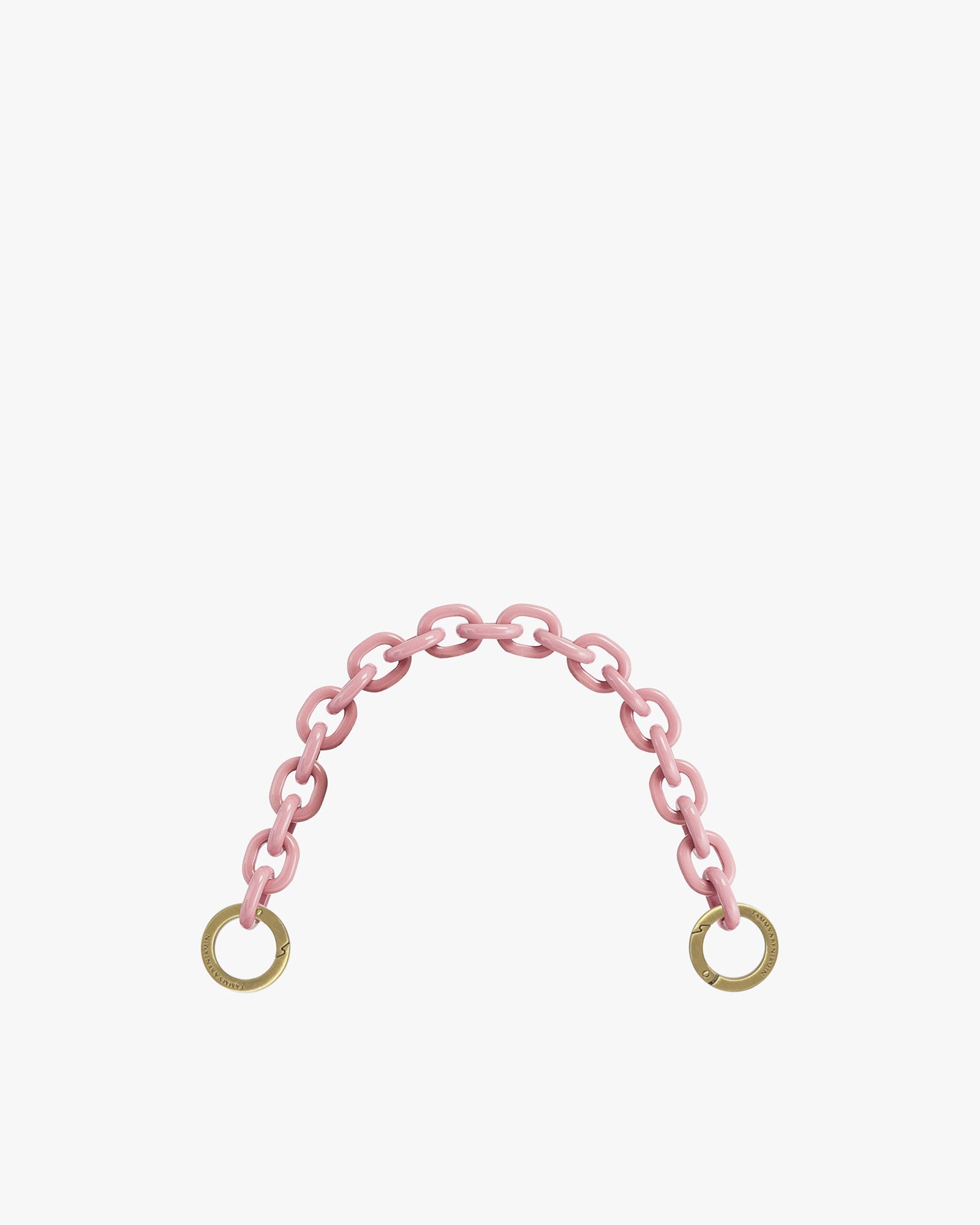 Short resin chain in smoky pink, oval links with engraved brass rings, laid in an arc on white background