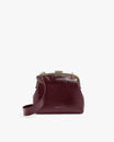 Sac EMMA bordeaux naplak de face, posé, avec bandoulière longue attachée et fermoir doré