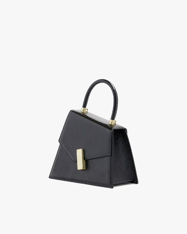 Sac CUBIST en noir naplak, vue de trois quarts, posé, fermoir doré et anse supérieure visibles