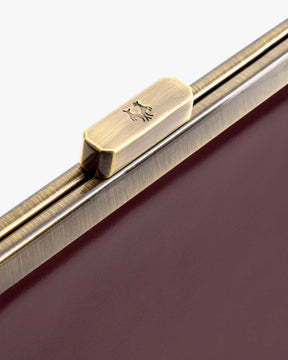 Sac JEANNE BAGUETTE Mahogany, détail du fermoir rétro gravé sur le rabat bordeaux