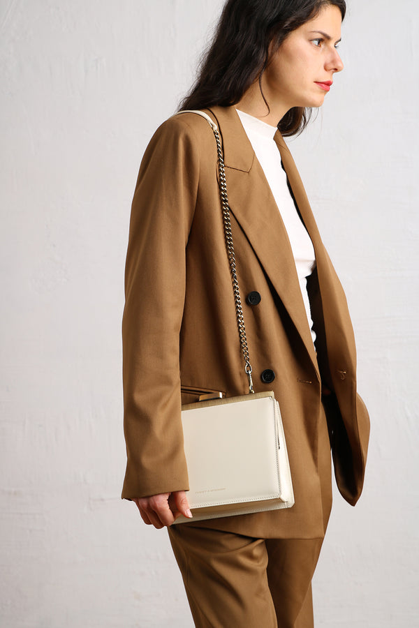Sac JEANNE Ivoire porté en bandoulière avec chaîne, vue de profil sur veste camel