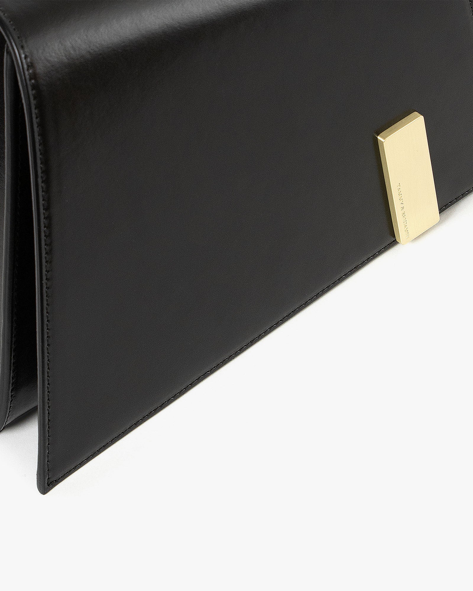Sac TARA noir, gros plan sur le rabat et le fermoir rectangulaire doré