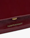 THEA MINI bag in Bordeaux naplak, close-up on the gold clasp and embossed logo on the flap