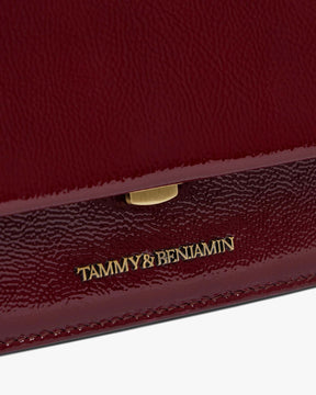 THEA MINI bag in Bordeaux naplak, close-up on the gold clasp and embossed logo on the flap
