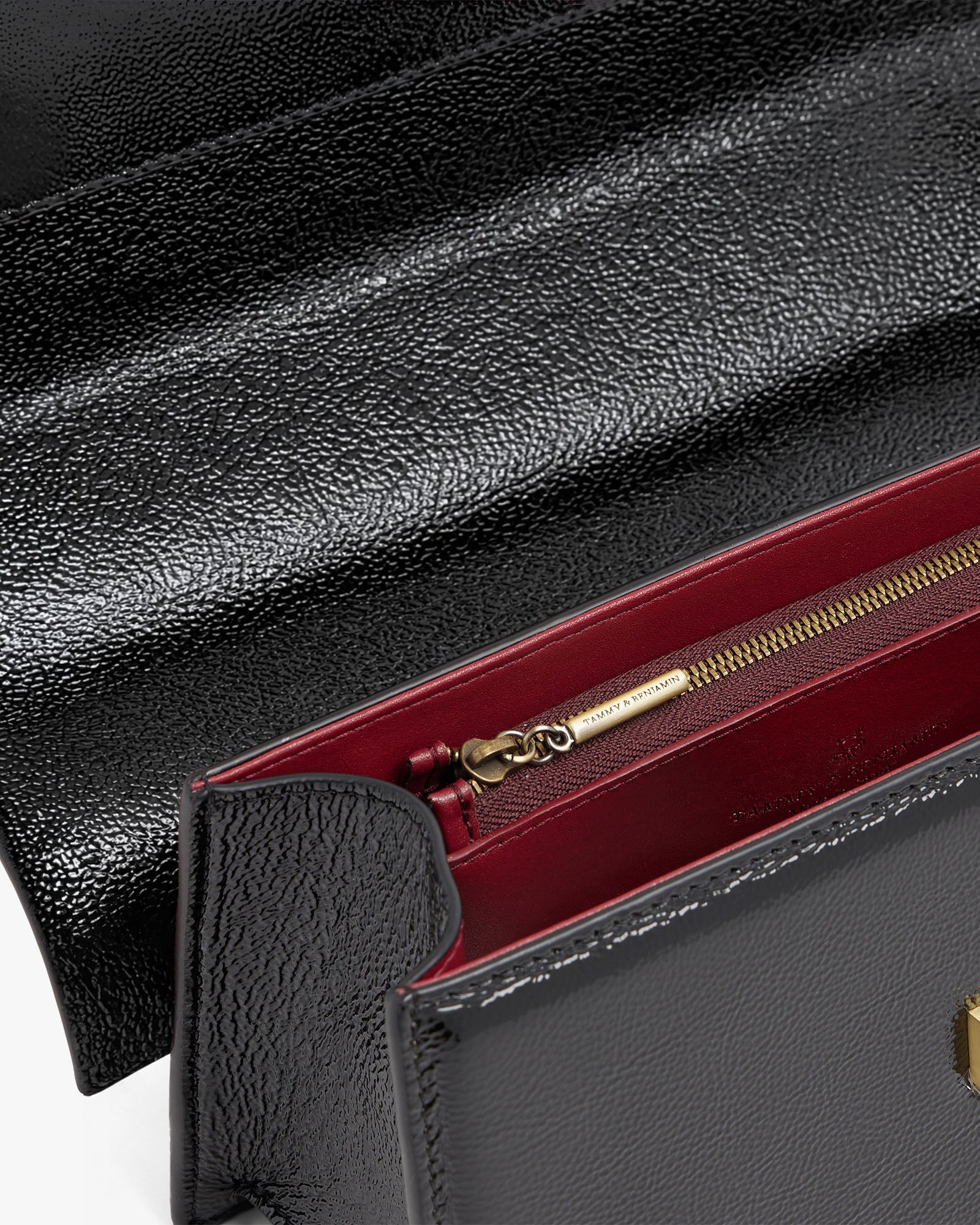 Sac THEA noir naplak, vue rapprochée intérieur avec poche zippée doublure bordeaux et fermoir doré