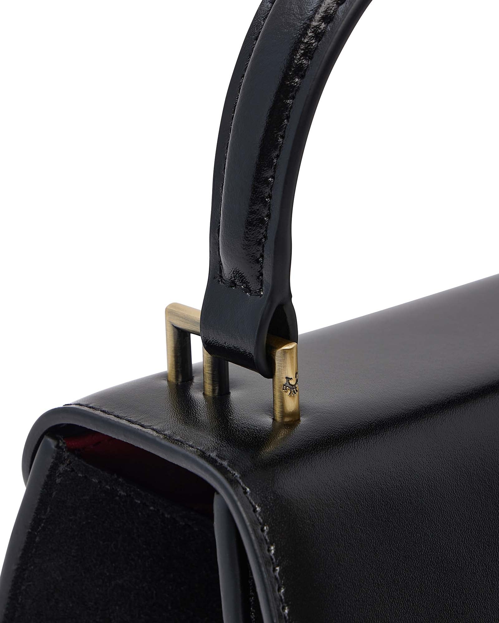 Sac ALEXIA NANO noir, détail de la poignée et des fixations en métal doré sur le rabat