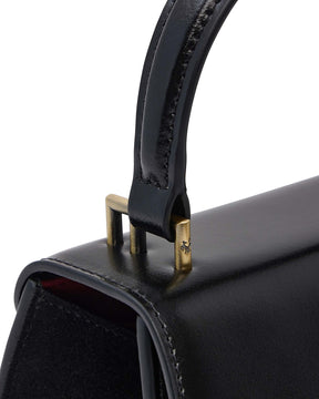 Sac ALEXIA NANO noir, détail de la poignée et des fixations en métal doré sur le rabat