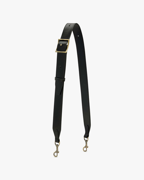 BANDOULIÈRE AJUSTABLE LARGE in black leather, laid flat, showing aged brass buckle and clasps