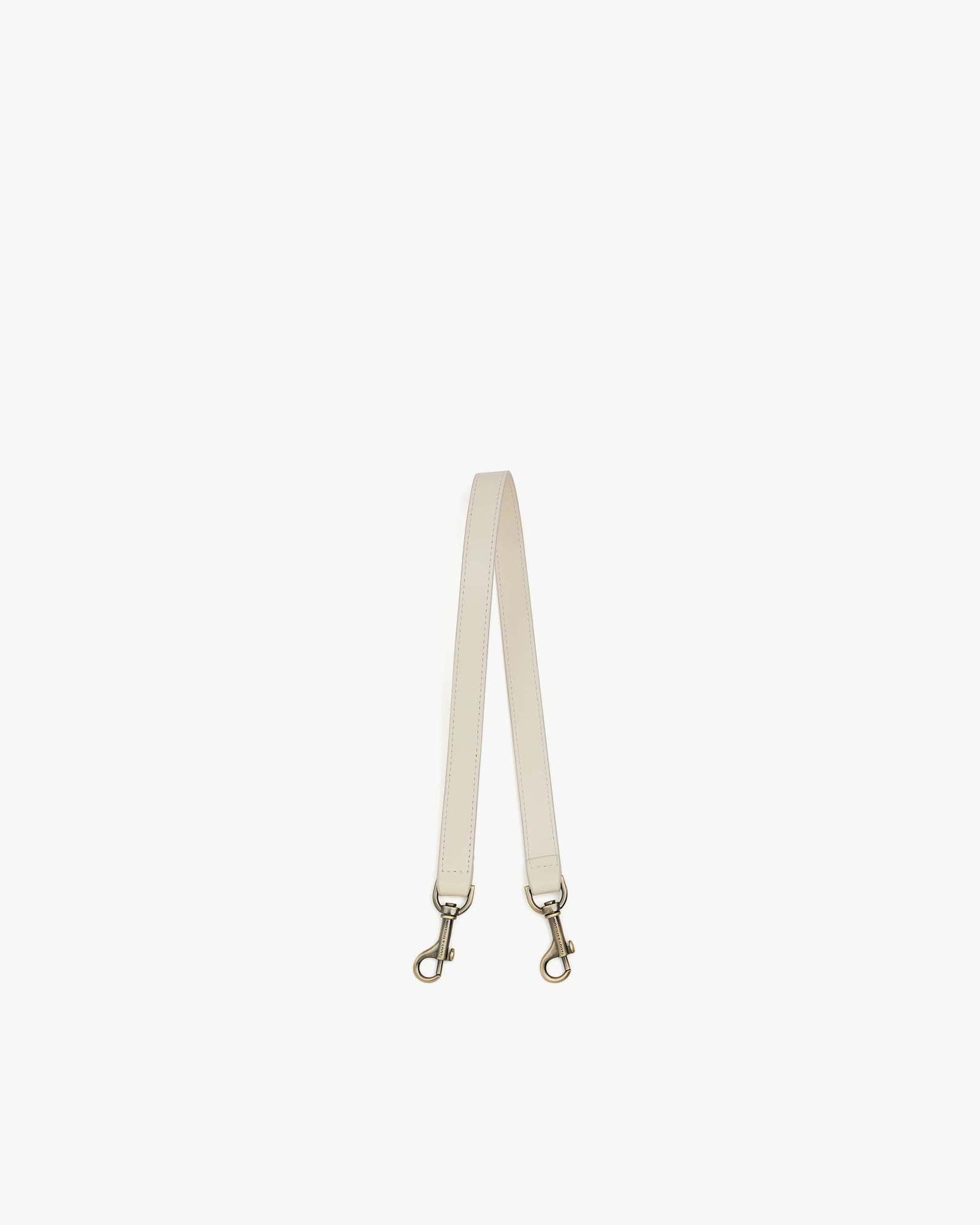 Short strap in leather, Ivoire, laid flat showing both aged brass clasps