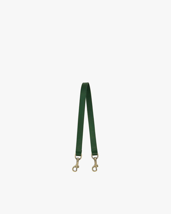 Short strap in emerald green leather, laid in a V shape, aged brass clasps at both ends