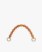 Chaîne courte en résine ambre, posée en arc, maillons ovales et anneaux en laiton vieilli gravés aux extrémités