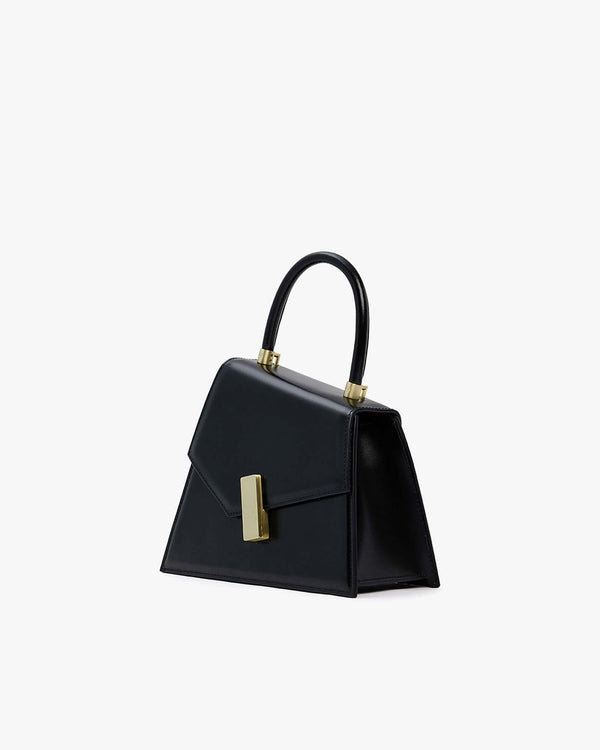 Sac CUBIST noir vu de trois-quarts, poignée relevée, fermoir doré rectangulaire en gros plan