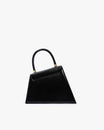 Sac CUBIST noir, vue de face, silhouette trapézoïdale asymétrique, anse ronde et fermoirs dorés