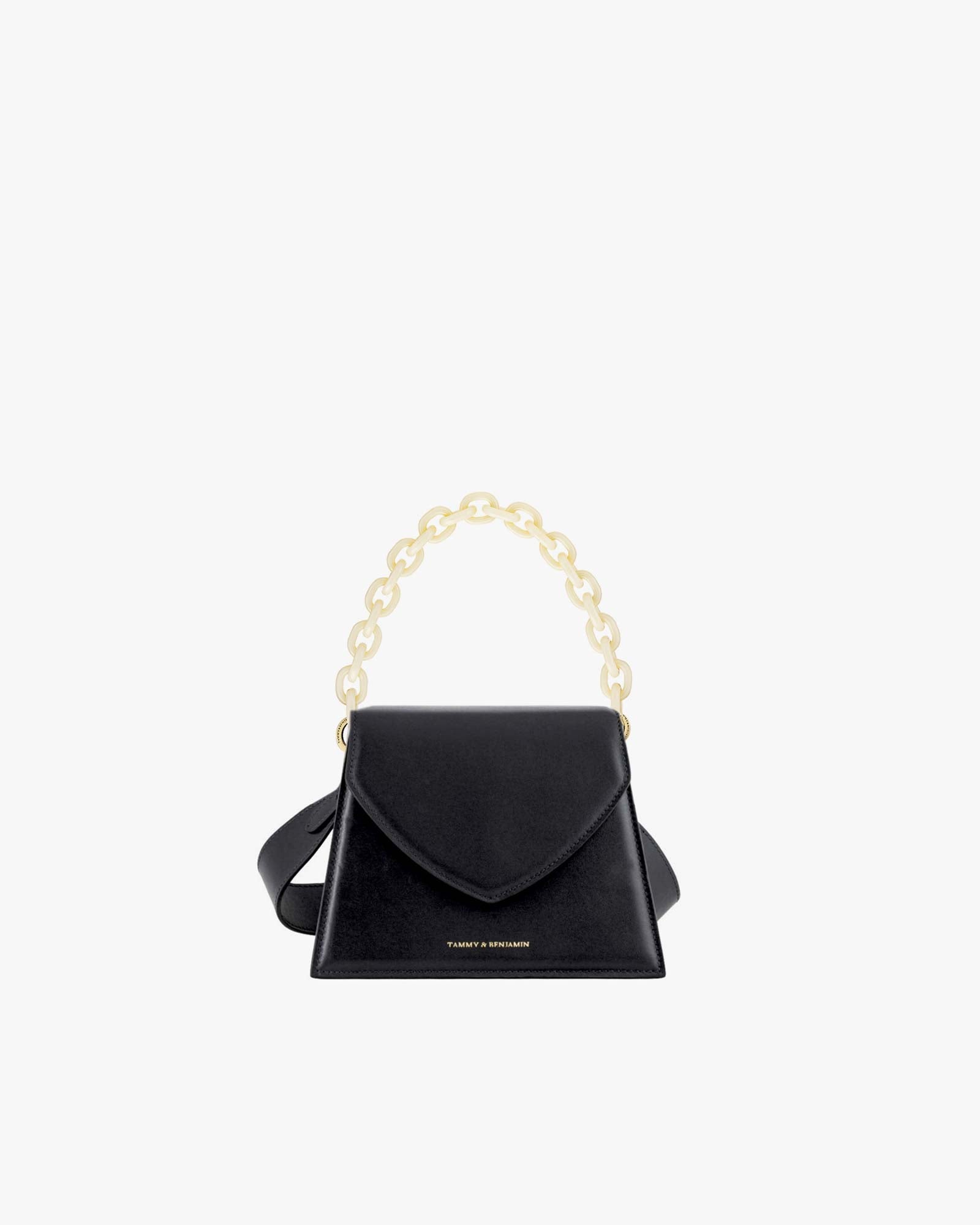 Sac GABRIELLE noir de face, porté à la main par son anse chaîne dorée, posé sur fond blanc
