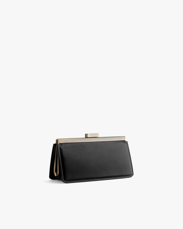 Sac JEANNE BAGUETTE noir de trois quarts, posé, fermoir rétro doré apparent