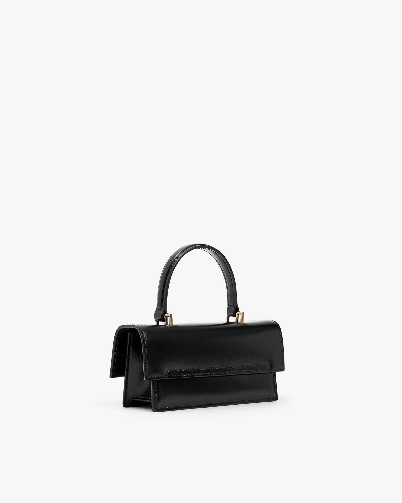 Sac THEA MINI noir, vue de trois quarts arrière, posé, anse courte rigide et rabat oversize visibles