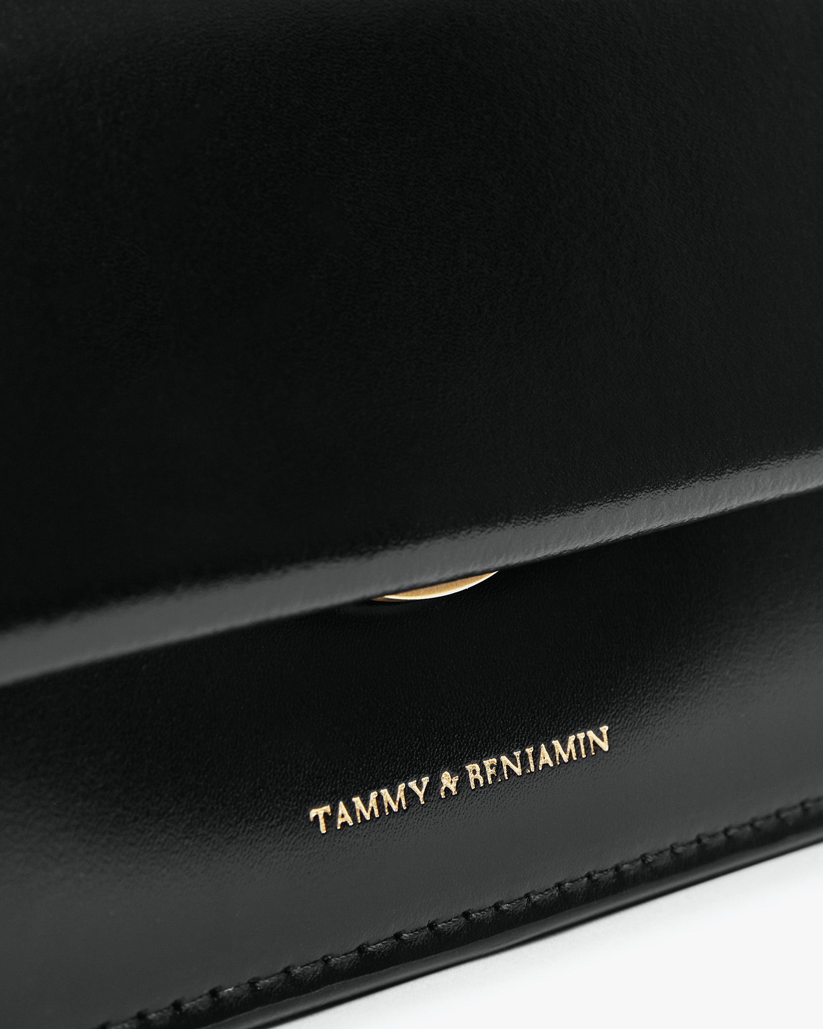 Sac THEA MINI noir, gros plan sur le rabat et le logo doré Tammy & Benjamin